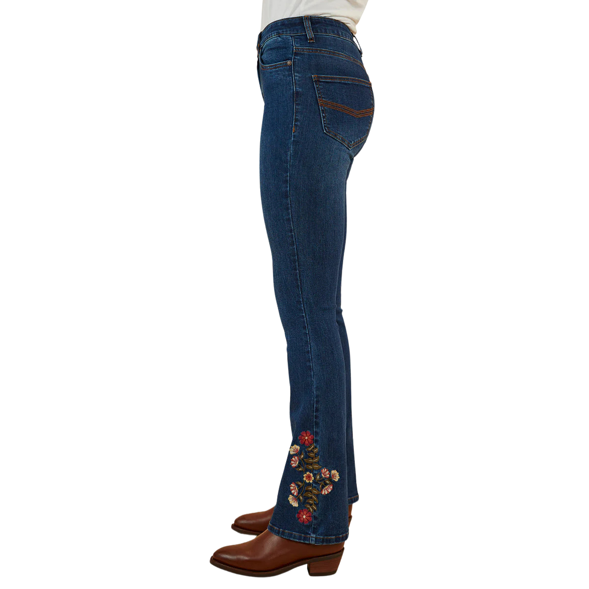 A side profile of a woman wearing classic blue Ringers Western Women's Penny Rodeo High Rise Bootleg Jeans (222104RW) showing colourful floral embroidery on the left ankle, paired with brown leather boots against a plain white background.