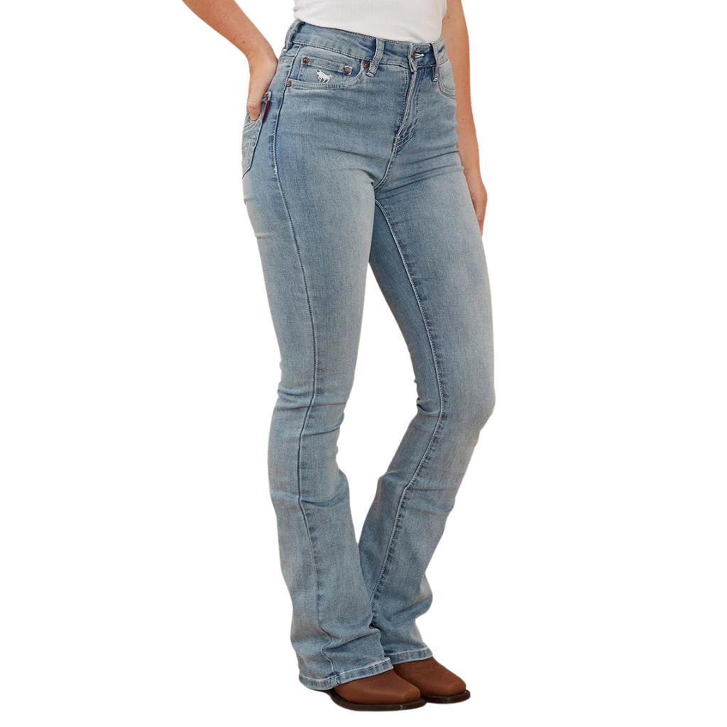 A woman wearing light blue Ringers Western Women's Penny Rodeo High Rise Bootleg Jeans (222104RW) with metallic embroidery on the back pockets, paired with a white top and brown boots, shown from the waist down against a plain white studio background.
