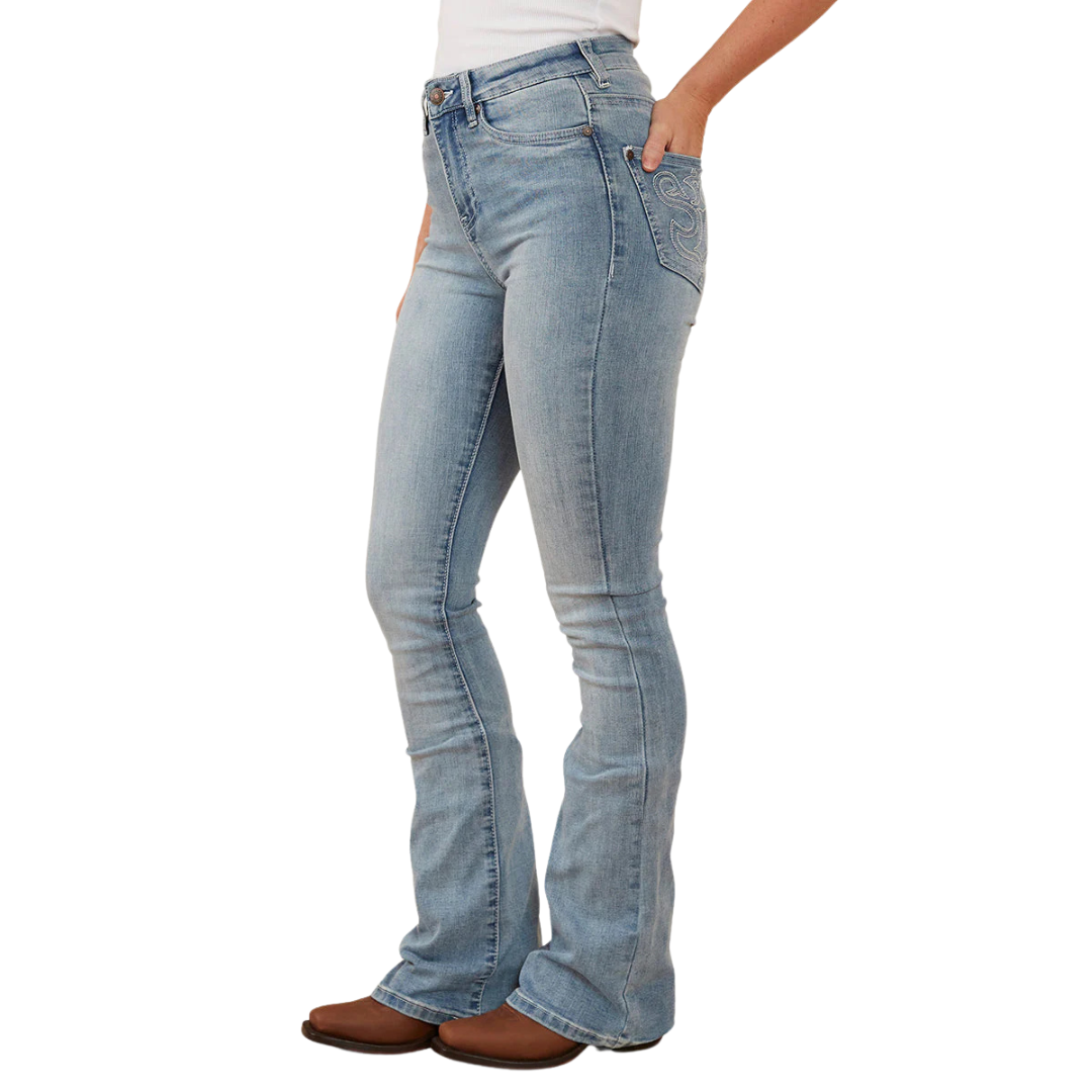 A woman in profile wearing light blue Ringers Western Women's Penny Rodeo High Rise Bootleg Jeans (222104RW) with a white top and brown boots, shown from the waist down against a plain white studio background.