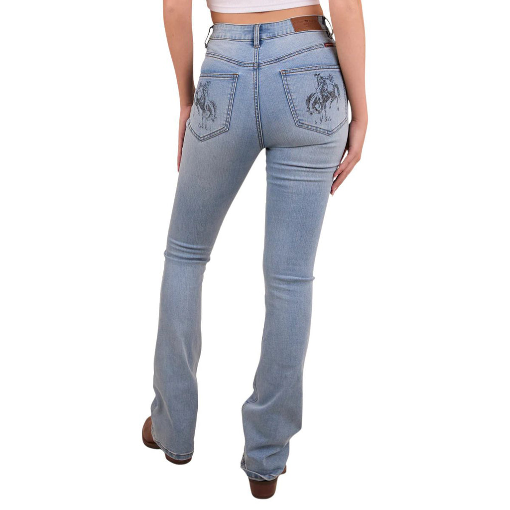 A woman viewed from behind from the waist down modelling vintage light blue Ringers Western Women's Penny Rodeo High Rise Bootleg Jeans (222104RW) with a black rodeo rider print on the back pockets, paired with a brown belt, boots and a white crop top on a white studio background.