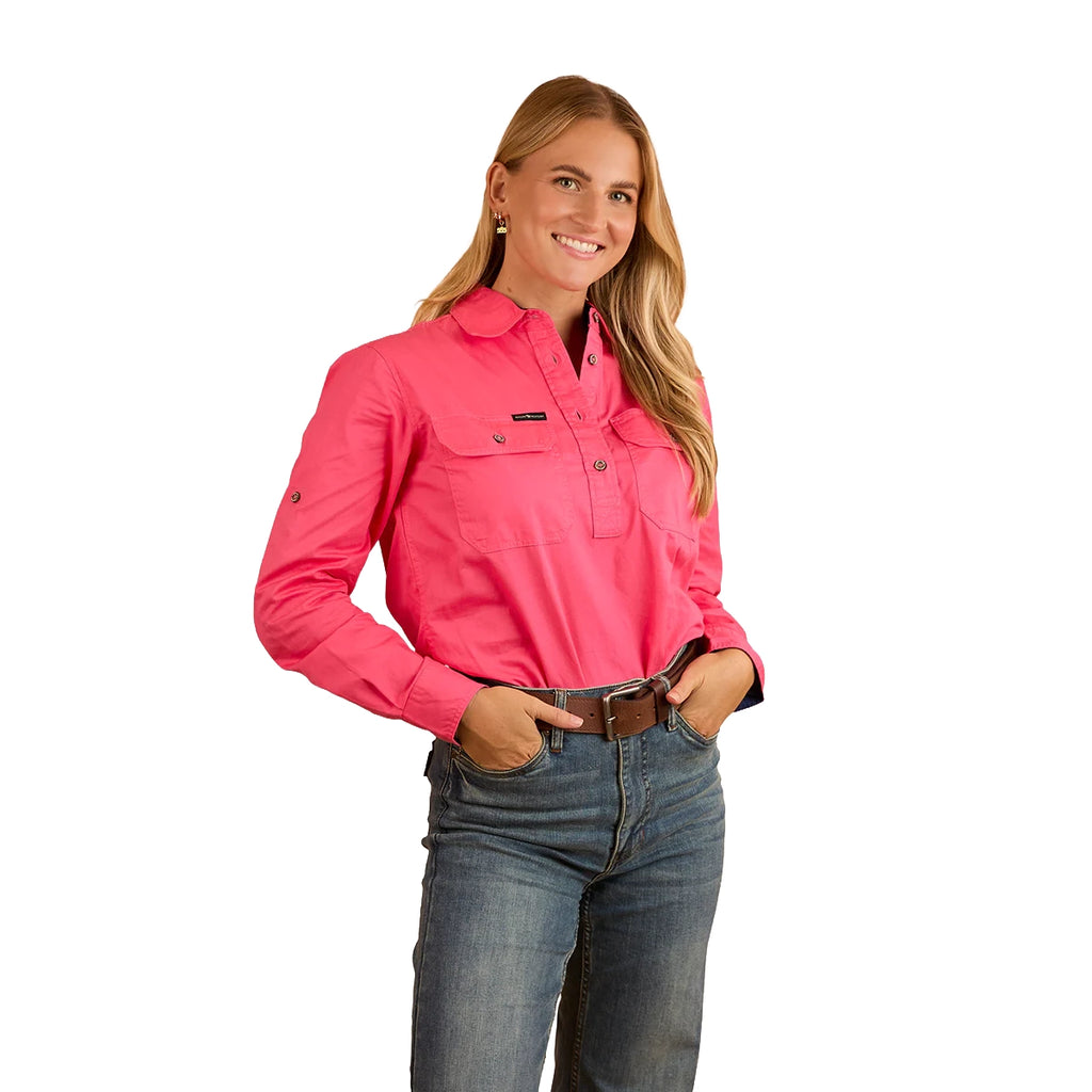 A woman with long blonde hair smiles, wearing the Ringers Western Womens Pentecost River Half Button L/S Work Shirt in Melon and blue jeans. She stands against a white background with her hands in her front pockets.