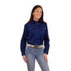 A woman with long dark hair smiles, wearing a Ringers Western Womens Pentecost River Half Button Work Shirt in Navy and blue jeans with a light coloured belt. The background is plain white.