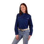 A woman with long dark hair smiles, wearing a Ringers Western Womens Pentecost River Half Button Work Shirt in Navy and blue jeans with a light coloured belt. The background is plain white.
