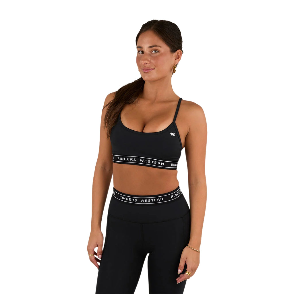 A woman wears the Ringers Western Womens Ringers Active Logo Elastic Essential Crop Top (225013RW) in black, featuring adjustable straps and "Ringers Western" branding, paired with matching high-waisted leggings, against a white background.