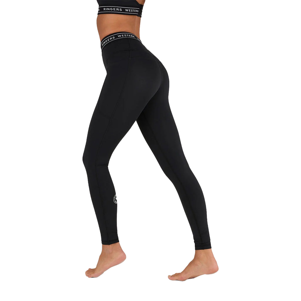 A model wears Ringers Western Womens Ringers Active Logo Elastic Pocket Leggings (225015RW) in black recycled polyester, featuring a high waist, visible logo waistband, and shown mid-step barefoot against a white background.