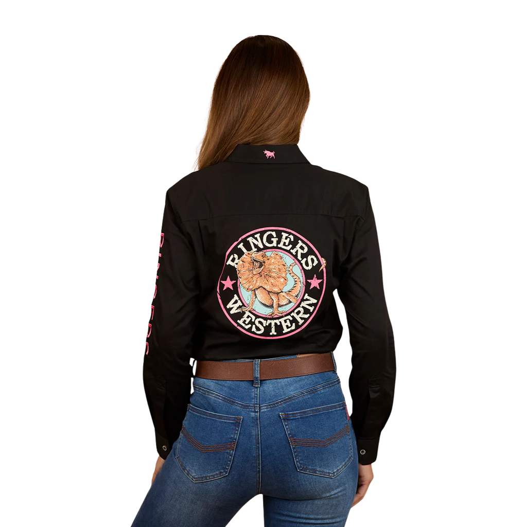 A woman with her back to the camera wears a black Ringers Western Womens Signature Jillaroo Printed Full Button L/S Work Shirt (225101RW) featuring a large logo and bull graphic, paired with blue jeans. She has brown hair down against a plain white background.