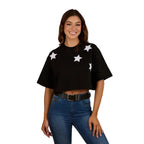 A woman wearing a Ringers Western Womens Twilight Oversized Cropped S/S Tee (225059RW) in black, paired with blue jeans and a black belt, smiles while standing against a plain white background.