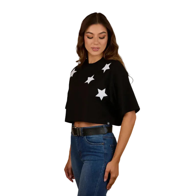 A woman wearing a Ringers Western Womens Twilight Oversized Cropped S/S Tee (225059RW) in black, paired with blue jeans and a black belt, smiles while standing against a plain white background.