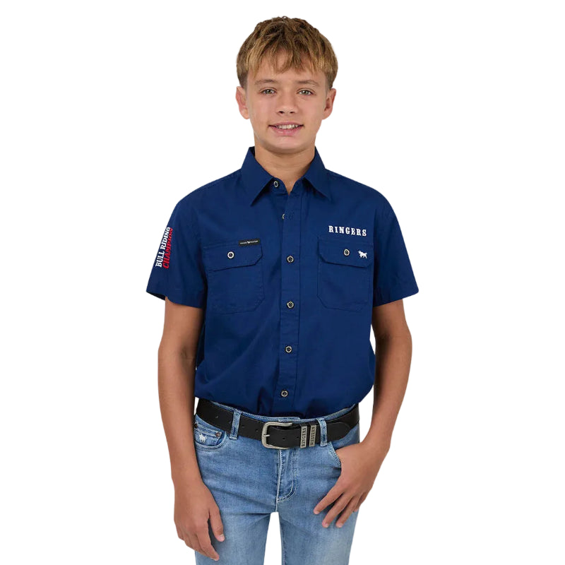 Young boy wearing a blue work shirt with visible branding on a plain background