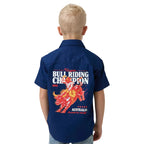 A child viewed from behind wearing a navy blue short-sleeve button-up shirt with a large red, orange, and white bull riding graphic and text on the back, paired with light blue jeans against a white studio background.