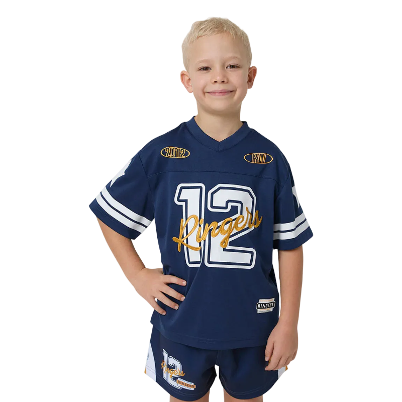 A young boy with blonde hair wearing a navy blue football jersey and matching shorts set. The jersey features the number 12 in white with a black outline, a gold script 'Ringers' logo across the chest. 