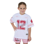 Young girl wearing a white sports jersey with red and pink details on a white background