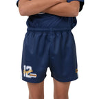 A close-up of a person wearing navy blue footy shorts with a white and yellow number 12 graphic on the left leg and a small circular logo on the right leg, paired with a matching navy top against a white background.