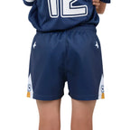 A close-up of a child wearing navy blue athletic shorts with white side panels, white star logos, and small crest details near the hem, paired with a matching navy jersey.