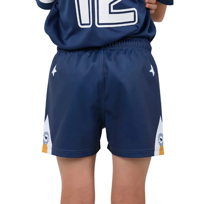 A close-up of a child wearing navy blue athletic shorts with white side panels, white star logos, and small crest details near the hem, paired with a matching navy jersey.