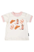 A baby t-shirt with a white body, light pink collar and sleeve cuffs, featuring a western-themed graphic print of cowboy hats, horseshoes, and boots in orange and pink.