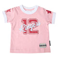 A baby pink short-sleeve t-shirt with a white ringer collar and cuffs, featuring a red '12' and light blue 'Ringers' script across the chest, with red star details on the sleeves and a brand label near the hem.