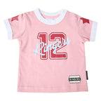 A baby pink short-sleeve t-shirt with a white ringer collar and cuffs, featuring a red '12' and light blue 'Ringers' script across the chest, with red star details on the sleeves and a brand label near the hem.