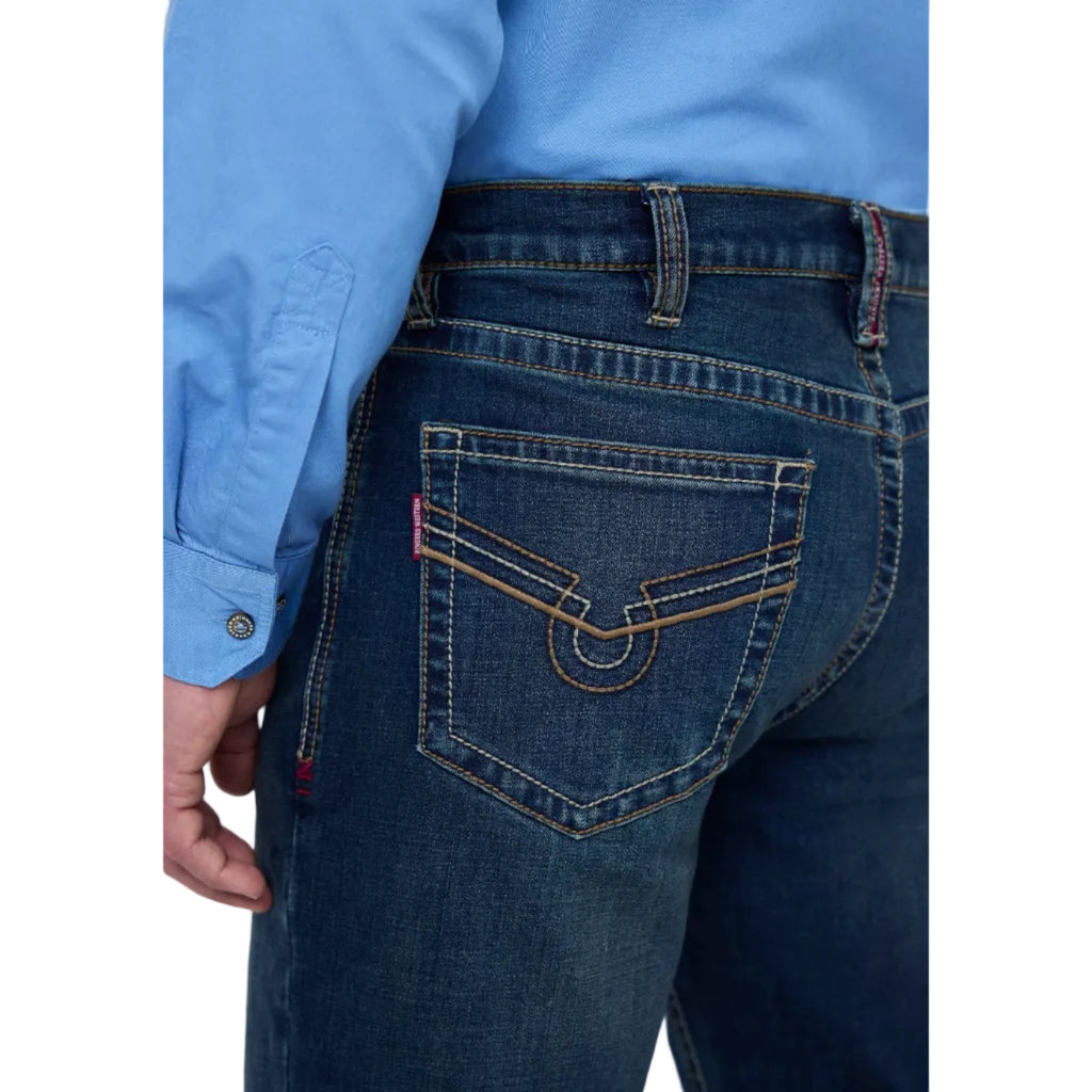 Close-up back view of a person wearing dark blue denim jeans with contrast tan stitching and a light blue button-up shirt.