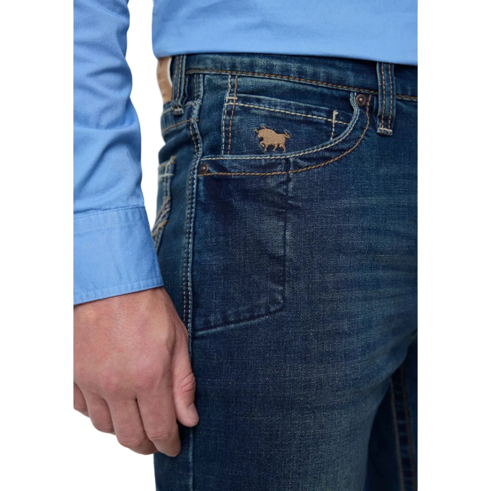 Close-up of a person wearing dark blue denim jeans with a small embroidered bull logo on the back pocket, paired with a light blue long-sleeve shirt.