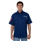 A man wearing a navy blue short-sleeve button-up shirt with 'RINGERS' printed in white on the left chest, paired with light blue jeans against a white background.