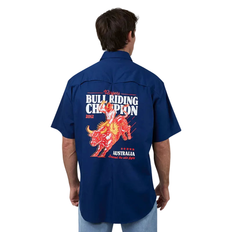 A man viewed from behind wearing a navy blue short-sleeve button-up shirt with a large red and white bull riding graphic on the back, paired with light blue jeans against a white studio background.