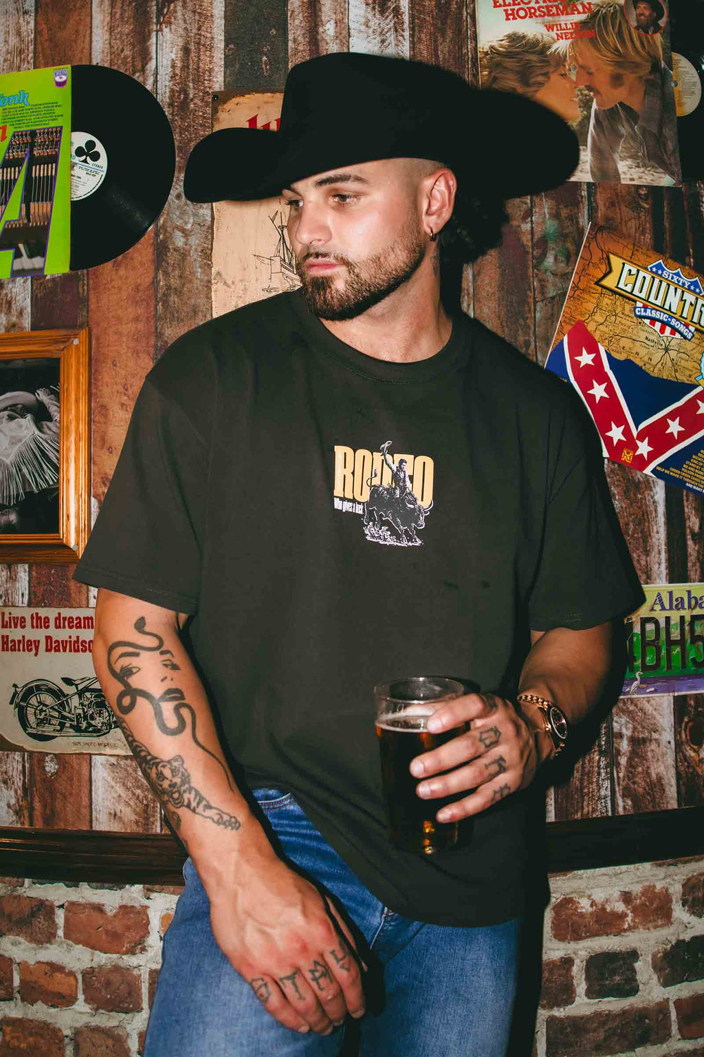 A man wearing a black cowboy hat and a black graphic t-shirt.
