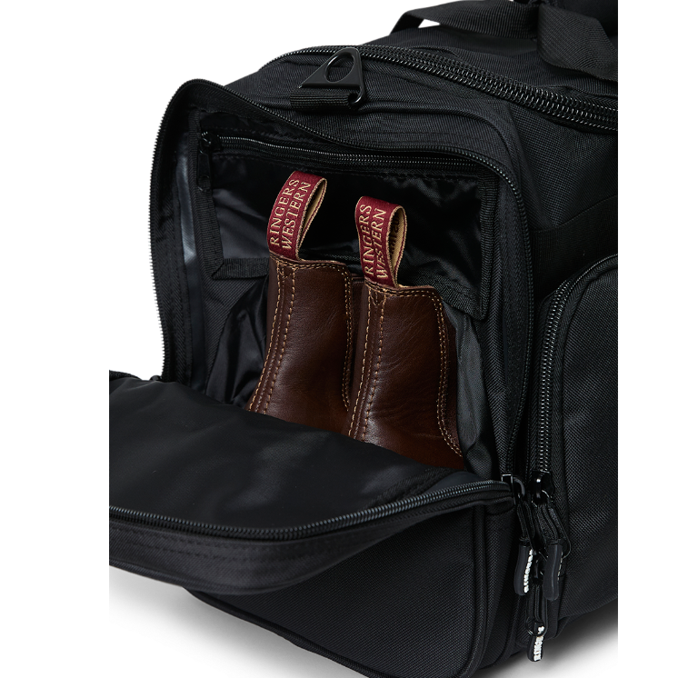 A black Ringers Western Rider Go Sports Bag (625130RW) duffel bag with 'Ringers' branding, featuring a top carry handle and showing the zipped end compartment with a pair of brown chelsea boots in it.