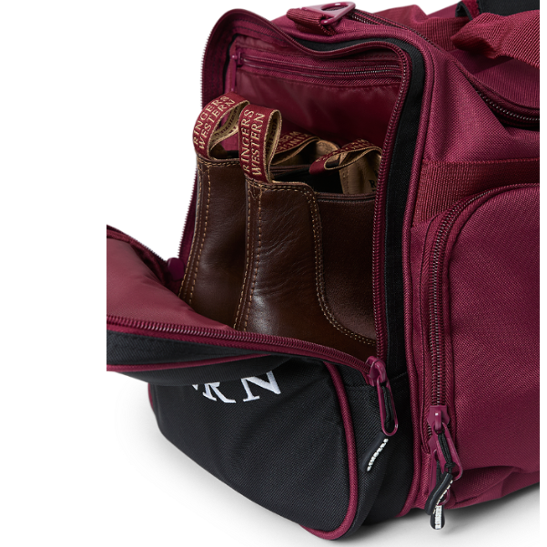 A close-up of a burgundy and black Ringers Western Rider Go Sports Bag (625130RW) duffel bag with white 'Ringers' branding, featuring dual top handles, a zippered pockets, with its side boot compartment open, showing brown leather shoes.