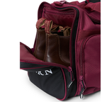 A close-up of a burgundy and black Ringers Western Rider Go Sports Bag (625130RW) duffel bag with white 'Ringers' branding, featuring dual top handles, a zippered pockets, with its side boot compartment open, showing brown leather shoes.