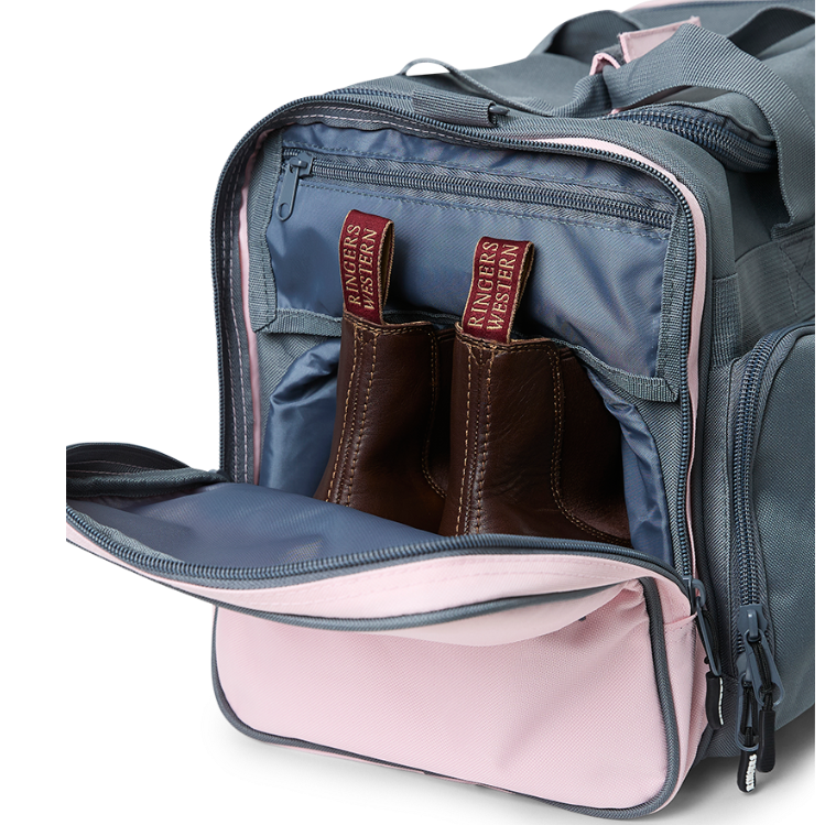 A charcoal and pastel pink Ringers Western Rider Go Sports Bag (625130RW) duffel bag with 'Ringers' branding, featuring a top carry handle and showing the zipped end compartment with a pair of brown chelsea boots in it.