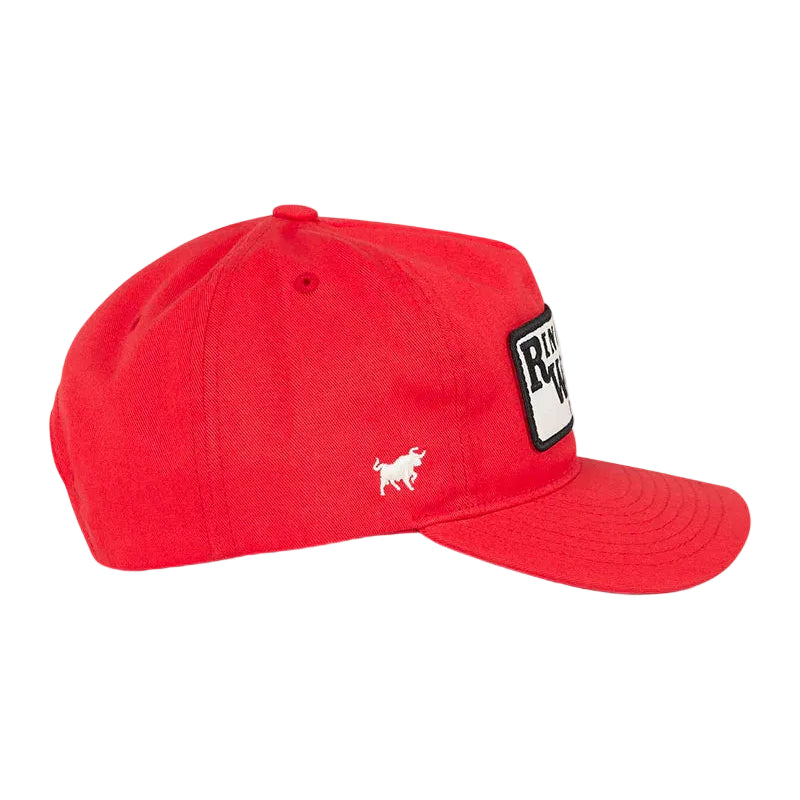 A red baseball cap with a white embroidered bull logo on the side and a black-and-white rectangular patch on the front, shown against a white background.