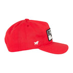 A red baseball cap with a white embroidered bull logo on the side and a black-and-white rectangular patch on the front, shown against a white background.