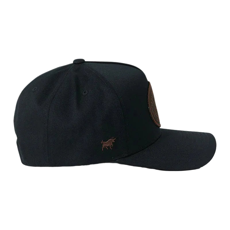 A black baseball cap with a small brown embroidered bull logo on the front and a brown circular patch on the side, shown against a white background.