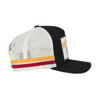 A black and white trucker-style cap with a curved brim, featuring a white mesh back, a black front panel and brim, and two horizontal stripes near the brim in yellow and red.