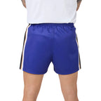 A close-up back view of a person wearing royal blue athletic shorts with white and black side stripes, paired with a white top against a white background.