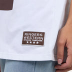 Close-up of a white shirt with a 'Ringers Western' patch on a plain background