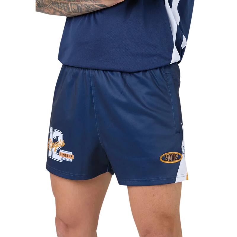 Close-up of a person wearing navy athletic shorts with white side panels, a white and navy top, and printed graphics including a large '12' on one leg and a gold '2012' emblem on the other leg.