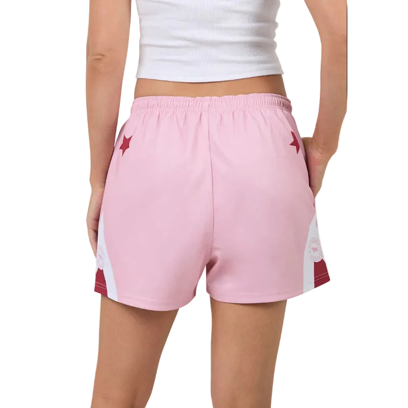 Pink footy shorts with white and red accents worn by a person on a white background