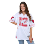 Woman wearing a white sports jersey with red and pink details on a plain background