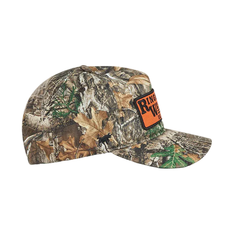 A camouflage baseball cap featuring a realistic woodland pattern of brown leaves, green branches, and gray bark, with an orange and black against a plain white background.