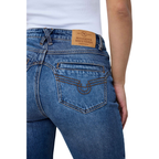 Close-up back view of a person wearing blue denim jeans with a tan leather Ringers Western waistband patch and a white top visible at the waist.