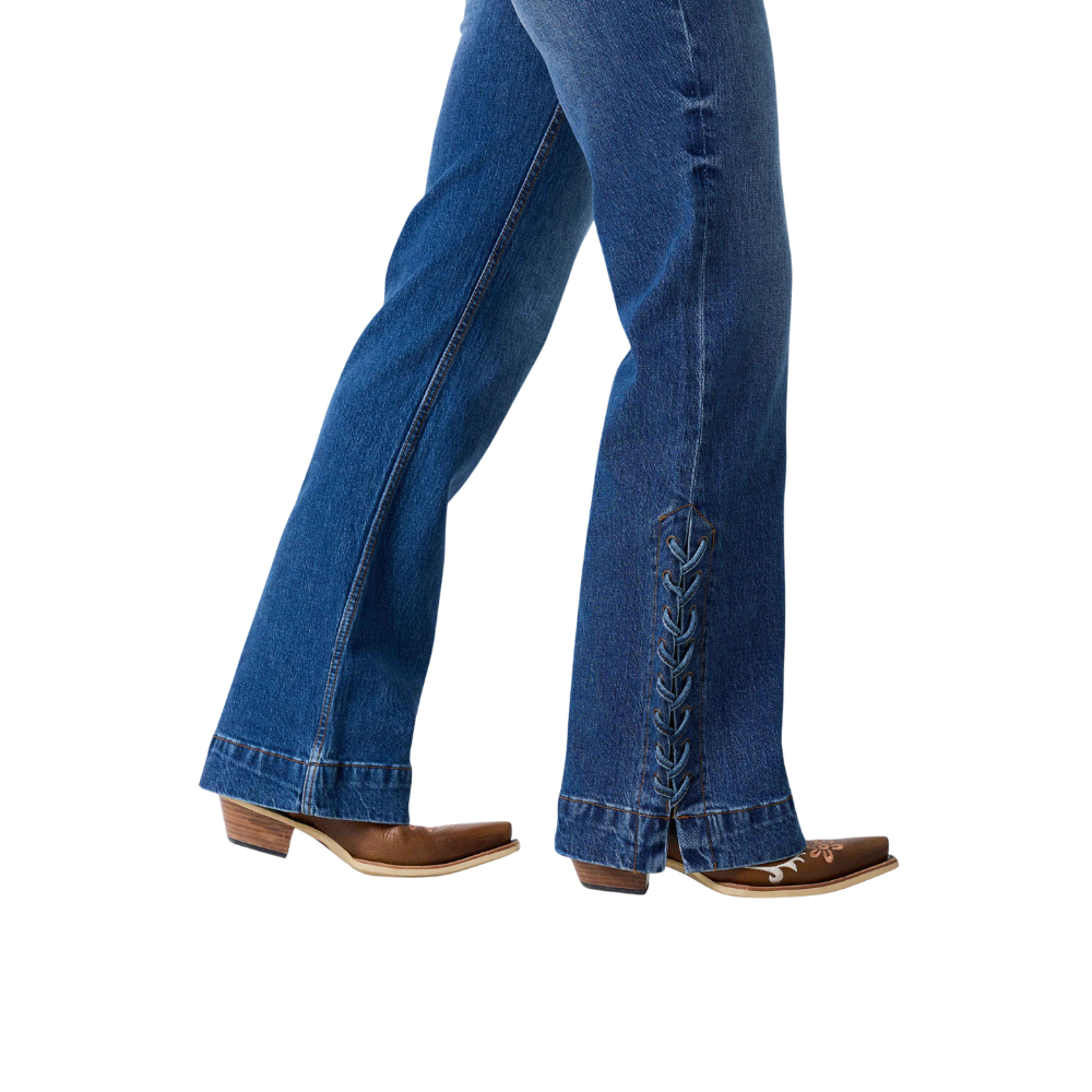 Close-up of a person's legs wearing blue denim jeans with decorative side lacing and brown cowboy boots, shown against a plain white background.