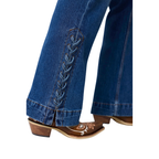 Close-up of blue denim jeans with decorative side lacing and split hems, paired with brown western-style boots on a white background.