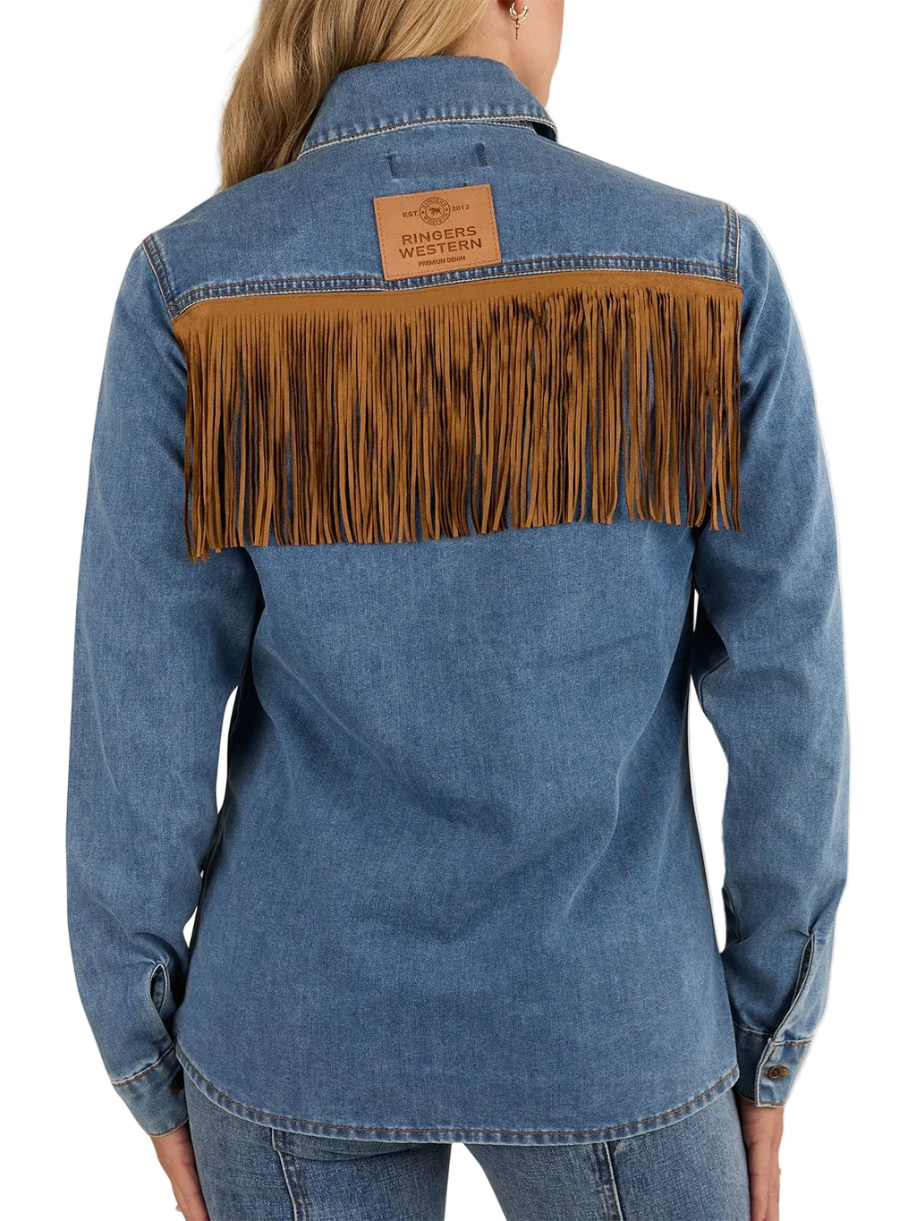 Back view of a blue denim shirt jacket with a wide brown faux-leather fringe panel across the shoulders and a tan leather patch on the upper back, shown on a model against a white studio background.