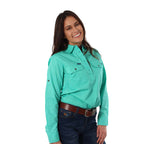 A woman with long dark hair, wearing a Ringers Western Womens Pentecost River Half Button Work Shirt in Mint and blue jeans with a brown belt. The background is plain white.