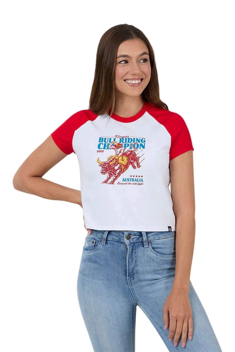 A woman modeling a white and red raglan t-shirt with a colorful bull riding graphic on the front, paired with light blue jeans, against a solid white background.