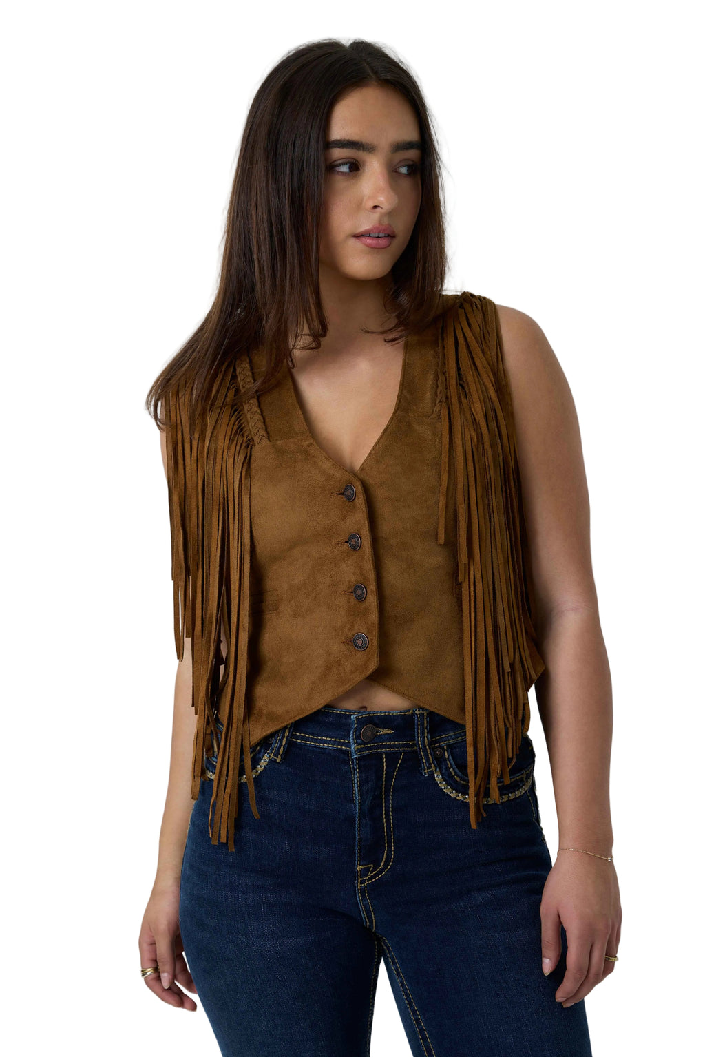 A woman wearing a brown suede fringe vest over a matching brown top, paired with dark blue jeans, photographed against a white studio background.