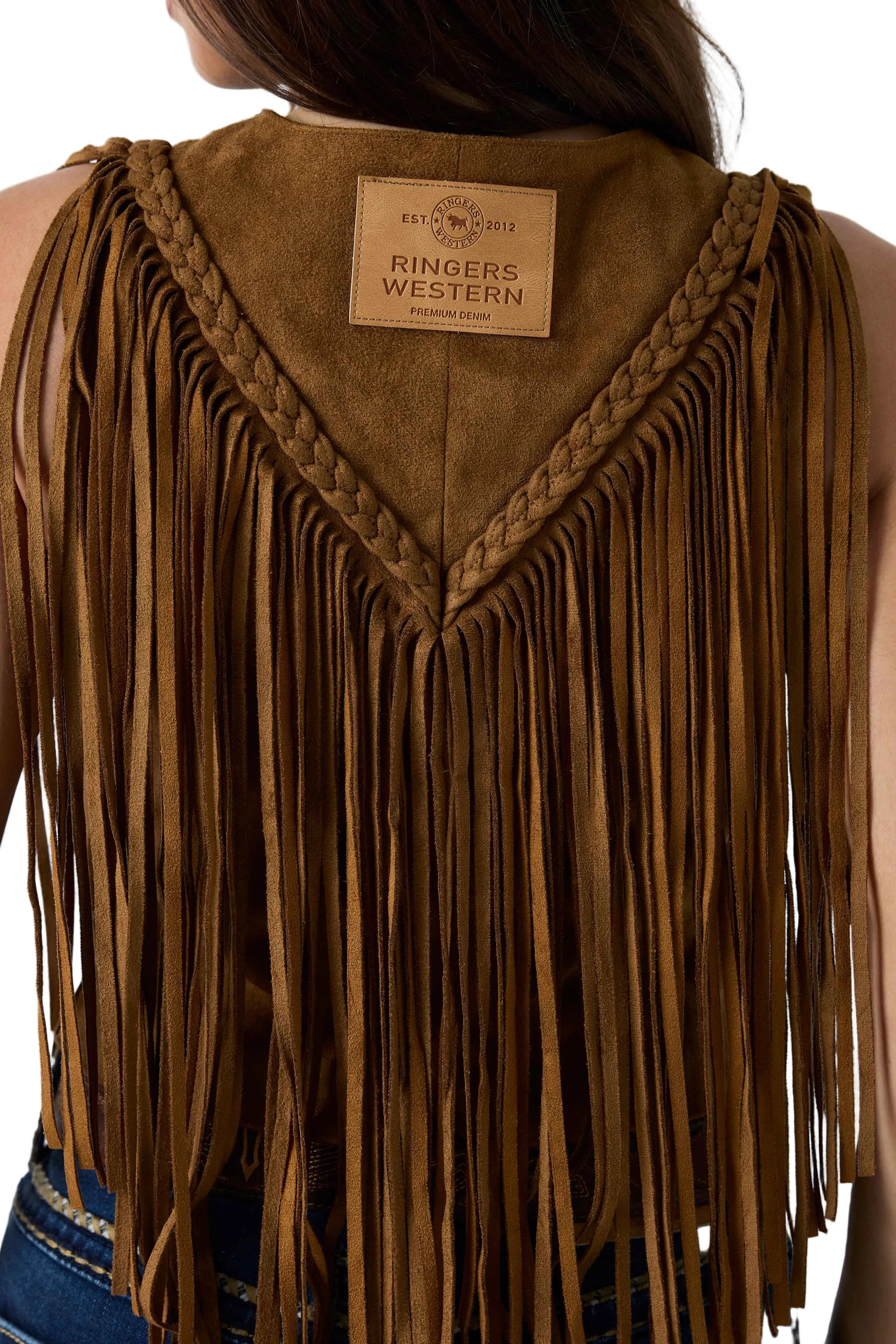 Close-up back view of a person wearing a brown suede fringe vest with braided trim and a visible Ringers Western label at the neckline.