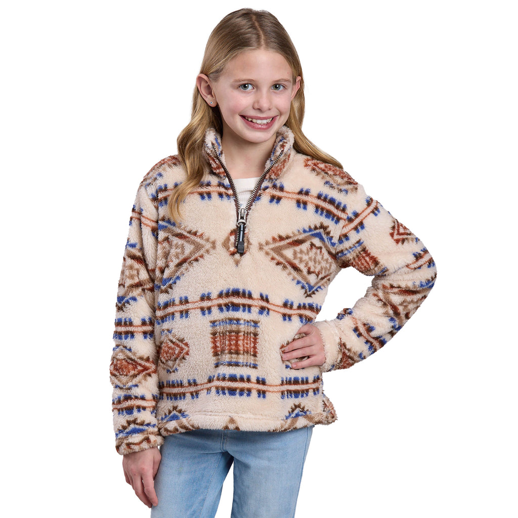 A smiling young girl with long blonde hair poses in light blue jeans and the Roper Girls L/S Pullover (29250120) Brown by Roper, a fuzzy polar fleece with blue and brown geometric patterns, set against a white background.